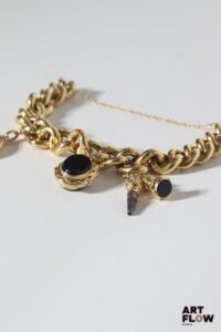 Bracelet gourmette en or jaune 18k (750/°°) à larges mailles et charm’s. Poids brut : 40,71 gr