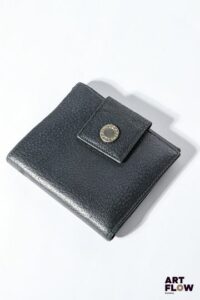 BULGARI Porte feuille en cuir noir, bijouterie en métal argenté, fermoir à pression sous rabat. Dimensions : 10 x 11 cm Bon état général (quelques marques d'usage)