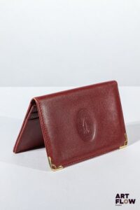 CARTIER Porte feuille en cuir rouge, bijouterie en métal doré. Dimensions : 8 x 11 cm Usures