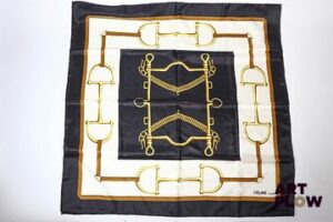 CELINE Paris Carré de soie à imprimé à décor de mors à chevaux sur fond noir et crème. Dim. : 85 x 85 cm Petites tâches et fils tirés