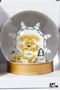 CHANEL Beauté Boule à neige figurant un flocon derrière un flacon de parfum « N°5 » entouré de paquets cadeaux. Signée. H. 12 cm Edition limitée Dans sa boîte d’origine Etat neuf
