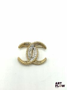 CHANEL Broche en métal doré pavée de strass Signée H. 3 cm x L. 3,5 cm