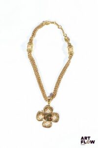 CHANEL - GRIPOIX Collection Automne/Hiver 1996 Collier en métal doré orné d'un pendentif formant un trèfle décoré de cabochons en pâte de verre nacrée et monogrammé Chanel au centre Chaines entrecoupées de motifs carrés ornés de pierres en pâte de verre du même coloris Fermoir décoré du logo Chanel, et inscription sur la plaque "96 A" La Maison Gripoix, fondée à Paris à la fin du XIXᵉ siècle, est célèbre pour sa technique artisanale de pâte de verre imitant les pierres précieuses. Gabrielle Chanel va ainsi collaborer étroitement avec Gripoix pour créer des bijoux audacieux mêlant inspiration antique et modernité. Longueur : 48 cm Très bon état général. Infimes rayures d'usage.
