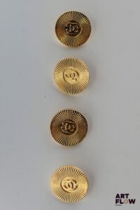 CHANEL Lot de 4 boutons en métal doré à décor guilloché rayonnant et sigle Chanel.