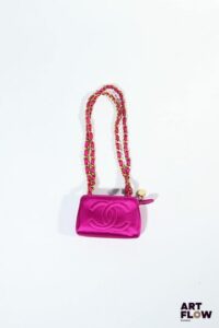 CHANEL Micro-sac en satin fuschia, bandoulière en chaine dorée et satin, fermeture zippée. Années 1990 Dim. : H. 8 x L.13 cm x P. 4,5 cm