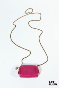 CHANEL Micro sac/trousse en cuir grainé framboise, chaine bandoulière en métal doré, fermeture zippée. Années 1990 Dim. : 10,5 x 7 x 5 cm Petites usures. Bandoulière ajoutée.