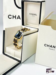 CHANEL Modèle "Ma Première" Montre bracelet femme en plaqué or, à mouvement à quartz, le boîtier octogonale à cadran à fond noir, index muets, aiguilles dorées, verre facetté, le bracelet en cuir noir et métal doré Diamètre 26 x 20 mm Longueur du bracelet : 13,5 cm env. Référence H0001 Bon état général Pile à remplacer, mécanisme non garanti. La Chanel Première est lancée en 1987 par la maison Chanel, marquant son entrée dans l’horlogerie féminine. Inspirée du flacon du Chanel No. 5 et de la place Place Vendôme, elle se distingue par son boîtier octogonal et son bracelet chaîne élégant.