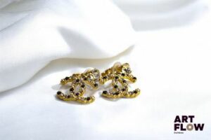 Chanel Paire de boucles d'oreilles dormeuses en métal doré ornées d'un strass, retenant le double C entrelacé en pampille. Très bon état
