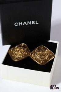 CHANEL Paire de clips d'oreilles en métal doré de forme carrée. Dims : 3 x 3 cm environ Dans leur boîte d'origine.