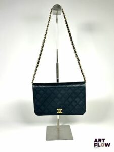 CHANEL Sac pochette en agneau matelassé noir, bijouterie en métal doré, fermeture par bouton pression, chaine escamotable. Circa 1980 Dimensions : H. 16 x L. 24 cm Dans sa boîte d'origine. Avec certification Entrupy