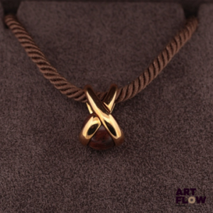 CHAUMET Pendentif en or jaune en forme de lien croisé, serti d’une boule de bois précieux, coulissant sur une cordelette de coton, les extrémités en argent. Le pendentif signé « Chaumet Paris » et numéroté 329787. Dans son écrin, état parfait du pendentif et du cordon. Poids du pendentif : 4.67 g