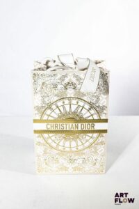 CHRISTIAN DIOR Boule à neige, l'intérieur figurant le logo CD dans un décor rayonnant, entouré de cadeaux et de sacs shopping H.14,5 cm Dans un sac Christian Dior Très bon état général