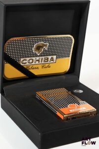 COHIBA Briquet en métal argenté laqué à décor géométrique noir et blanc Partie base du briquet de couleur orange 6,5 x 3,5 cm Dans son écrin Très bon état général