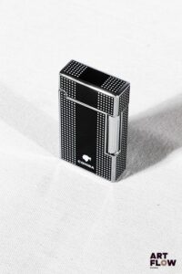 COHIBA Briquet en métal argenté laqué à décor géométrique noir et blanc. Partie base du briquet de couleur orange 6,5 x 3,5 cm Dans son écrin Très bon état général