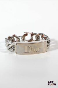 DIOR PARFUM Bracelet à mailles gourmettes larges en métal argenté ouvrant à un compartiment de gloss Bon état général (quelques traces d'oxydation)