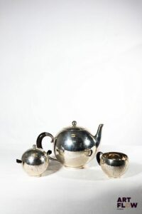 GEORG JENSEN Service à thé en argent comprenant une théière, un sucrier et un pot à lait, en métal délicatement martelé. Poinçons Gorg JENSEN, Danmark. Théière : H. 15 cm x D. 21 cm environ Sucrier : H.9,5 cm x D 12 cm environ Pot à lait : H. 6 cm x D. 11, 5 cm environ Poids brut : 843,68 g