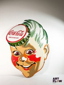 Grande plaque émaillée Coca-Cola à décor d'un visage Dimensions : 101 x 75 cm Petits éclats et traces de rouille