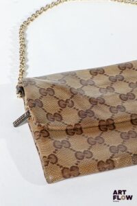 GUCCI Petit sac pochette en toile enduite monogrammée, bijouterie en métal doré, fermeture éclair. Dimensions : 14 x 19 cm