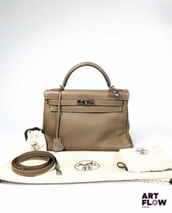 HERMÈS Kelly II Sac Kelly retourné 32 en cuir Taurillon Clémence étoupe, garniture en métal argenté Lettre K dans un carré : année 2007 Avec ses clés, clochette, cadenas, et bandoulière. Dimensions : 32 x 23 x 10,5 cm Facture incluse. Dans son pochon, sa boîte et son sac d'origine. Quelques marques d'usures, dont petites griffures et taches (voir photos).