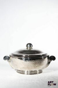 Jean DESPRES (1889-1980) Légumier couvert en métal argenté martelé reposant sur un talon. Signature à la pointe en dessous. H. 17,5 cm. Longueur. 32 cm environ. Très bon état général malgré quelques très légers défauts (petites rayures d'usage).