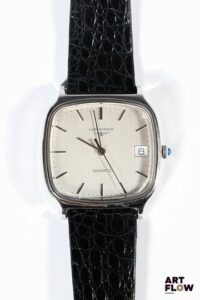 LONGINES Montre bracelet homme en acier, à mouvement à quartz, le boîtier de format Tv screen à cadran à fond brossé argenté, index bâton, guichet date à 3h, lunette lisse, cabochon en pierre synthétique bleu, le bracelet en cuir d'origine. Années 1970 33 x 31 mm Longueur du bracelet : 17 cm env. Longines, fondée en 1832 à Saint-Imier, est une maison suisse emblématique réputée pour sa précision chronométrique et son élégance intemporelle, notamment dans l’aviation et le sport. Très légères rayures d'usage. Non fonctionnelle au moment de la rédaction du catalogue, pile à changer.