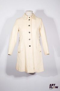 LOUIS FÉRAUD - Trench-coat "Mademoiselle Pluie Paris" - circa 1966 - Manteau 7/8 en vinyle beige, col rond, simple boutonnage, deux fausses poches verticales boutonnées, en rappel aux deux poches horizontales - Griffe noire, graphisme blanc - Taille présumée 36 - Bon état général malgré quelques défauts (craquelures)