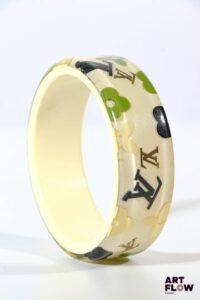 LOUIS VUITTON Bracelet "inclusion" en résine à fond crème et motifs multicolores. Diamètre : 6,5 cm Légères rayures d'usage