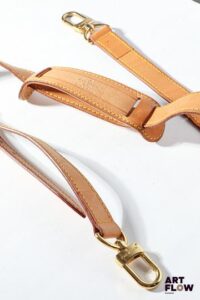LOUIS VUITTON Lanière de sac en cuir, bijouterie en métal doré Longueur : 99 cm On y joint une étiquette de voyage en cuir