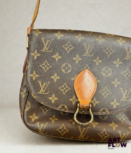 LOUIS VUITTON Modèle Saint cloud Sac besace en toile enduite monogrammée et cuir naturel, fermoir pression sur rabat, poche intérieure zippée et poche plaquée au dose, bandoulière réglable. Signé Tampon Louis Vuitton Paris Made in France Dim. H. : 20 cm x L. : 25 cm. Usures, craquelures, tâches.