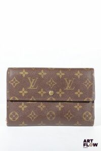LOUIS VUITTON Porte feuille en toile enduite monogrammée marron, bijouterie en métal doré, fermeture à pression sous rabat. Dimensions : 13 x 19 cm Usures