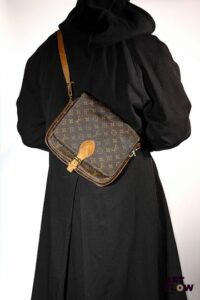 LOUIS VUITTON Sac cartouchière en toile enduite monogrammée et cuir naturel. Bandoulière à rabats fermé par une patte réglable. Dim. Larg. 27 cm. Haut. 23 cm. Profondeur. 7 cm. Usures, petits fils tirés et craquelures sur la toile