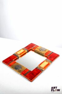 Marion de CRECY (née en 1954) - Fille de Mithé ESPELT Miroir rectangulaire en céramique émaillée de couleur rouge ocre à dorure craquelée à l'or liquide et décor géométrique de ronds et carrés incrustés de verre cristallisé dans les tons jaunes. Signé en bas à droite. Revers en feutrine noire. Avec certificat d'authenticité. 36 x 31 cm. Petit manque en haut à gauche.
