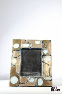 Mithé ESPELT (1923-2020) Miroir Ouvéa en céramique émaillée bleu et doré. Les parties dorées et celles en pâte de verre craquelées. Le dos gainé de feutrine verte. Dimensions : 31,5 x 27 cm Bon état général malgré quelques légers défauts (petites usures d'usage de l'émail).