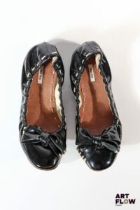 MIU MIU Paire de ballerines en cuir verni noir, ornées d'un noeud, surpiqûres beiges Pointure 35 État d'usage