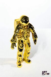 OMEGA Cosmonaute Omega Speedmaster en métal doré. Offert aux clients VIP de la marque. Figurine réalisée en édition limitée dans le cadre du 50 ème anniversaire d'Apollo 11. H. 14 cm Dans sa boîte d'origine Très bon état général