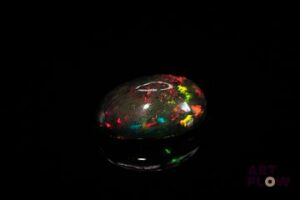 Opale noire cabochon ovale. Beaux éclats de couleur, dominante rouge, dominante verte. 7.54 cts. 17.0mm x 13.0mm