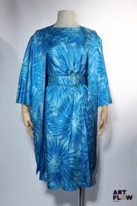PIERRE BALMAIN Haute couture Circa 1950 Provenance : Mme Geneviève de Gaulle Anthonioz, entrée au Panthéon en 2015 Robe de cocktail en soie imprimée d'un motif floral stylisé dans les tons bleus. Elle est composée d'une robe mi-longue à manches courtes à plissé ramassé sur la taille avec sa ceinture coordonnée et d'un manteau à manches 3/4 sans boutonnage, fendu sur toute la hauteur au dos, à finition noeud plat entre les épaules. Rehaussée de la rosette de la Légion d'honneur Taille présumée 36/38 Bon état général malgré quelques défauts (petites tâches, décousue par endroit, petits fils tirés)