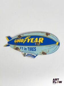 Plaque émaillée Good Year représentant un dirigeable Dimensions : 30 x 14 cm Petits éclats et traces de rouille Reproduction moderne