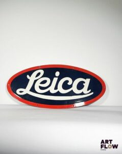 Plaque émaillée ovale Leica Dimensions : 34 x 76 cm Petits éclats et traces de rouille, légèrement tordue Reproduction moderne