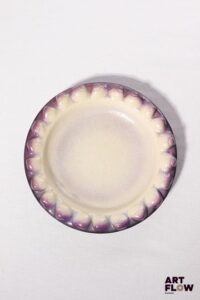 POL CHAMBOST (1906-1983) Plat 2106 "Coquillages" en faience émaillée à couverte polychrome dans les tons violets et blancs, l'aile ornée de coquillages. Incisé sous la base "2106, Poterie Pol Chambost, Made in France" D. 23,5, h. 4,5 cm