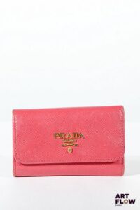 PRADA Porte clés en cuir saffiano rose, bijouterie en métal doré, fermeture à pression sous rabat. Dimensions : 6,5 x 10 cm Usures