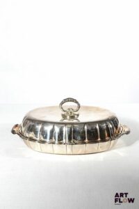 Ravier couvert en argent, de forme légèrement chantournée, les anses et le frétel à décor de volutes. De style Louis XV. Poids : 645,60 g Dimensions : H.10 x L. 26 cm environ