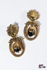 RÉMINISCENCE Paire de clips d'oreilles en métal doré à décor de coquilles, d'une fleur et de petits strass H. 7,5 cm Accident sur l'une des boucles (décrochage d'un élément)
