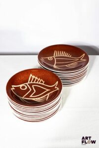 Robert PICAULT (1919-2000) - Vallauris. Importante partie de service en céramique émaillée à fond ocre, ornées d'un décor de poissons, comprenant : - 12 assiettes plates. D. 24 cm - 11 assiettes creuses. D. 20 cm. Cachet "Créations de PICAULT déposé" Très bon état général malgré quelques très légères traces d'usage (infimes sauts à la couverte sur certaines assiettes).