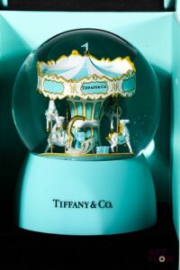 TIFFANY & CO Boule à neige faisant office de boîte à musique. L'intérieur figurant un caroussel. Édition limitée. Fonctionnelle. H. 15 cm. Dans son coffret d'origine Très bon état général