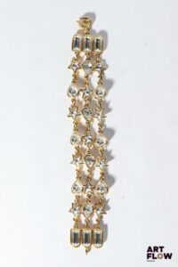 YVES SAINT LAURENT Manchette en métal doré orné de coeurs et étoiles arborants des cabochons composés de brillants Fermoir à anneau Longueur : 20 cm Signé sur le fermoir Bon état général