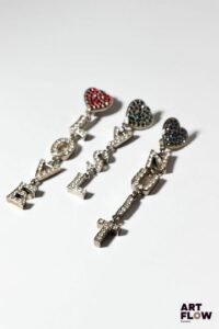 YVES SAINT LAURENT Trois clips d'oreilles ornés de coeurs retenant un lettrage en pampille LOVE/NUIT/YSL, à strass. L. 9 à 11 cm Manquent deux strass. Petites usures conformes à l'âge des pièces. Provenance : collection de la famille d'un ami et collaborateur de Robert Goossens.