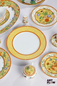 HERMÈS "La siesta D'Hermès" Rare partie de service en porcelaine à décor polychrome, particulièrement complet, de 95 pièces comprenant : - Douze assiettes de présentation (D. 30 cm) - Vingt-quatre assiettes à dîner (D. 27,5 cm) - Douze assiettes à dessert à décor de coings (D. 19 cm) - Douze assiettes à dessert à décor de citrons (D. 22,5 cm) - Douze tasses et sous tasses (D. 13 cm) - Deux plats creux (D. 29,5) - Un grand plat (D. 31,5 cm) - Un grand plat ovale (41 x 30 cm) - Un petit plat ovale (21 x 16 cm) - Deux saladiers (D. 24,5 cm) - Une saucière (L. 19 cm) - Un sucrier (H. 10 cm) - Un poivrier et salière Dans leur boîte d'origine.