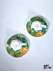 HERMÈS Modèle Passifolia Ensemble comprenant 2 tasses et leur sous tasse en porcelaine à décors imprimés et filet de couleur or sur le pourtour. Dessiné par Nathalie Rolland-Huckel. Diamètre : 15 cm pour la sous tasse