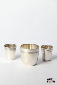 Paire de gobelets à liqueur en argent (Minerve), à décor de frises de plantes d'eau. Poids : 18,41 gr Accidents (enfoncements) On y joint une tombale en métal argenté.